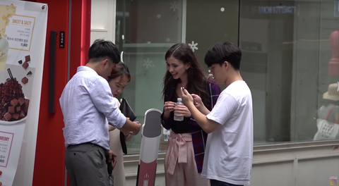 A white woman talking to Koreans outside a store