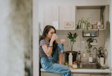 A young woman drinking milk sitting on the kitchen counter