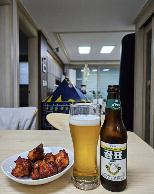 7Brau beer bottle and glass with chicken wings in an apartment