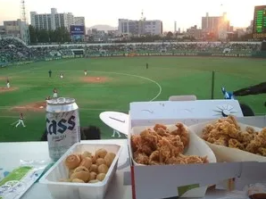 Korean fried chicken in takeout boxes and Cass beer before baseball green