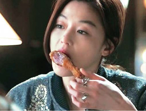 A woman eating a chicken leg