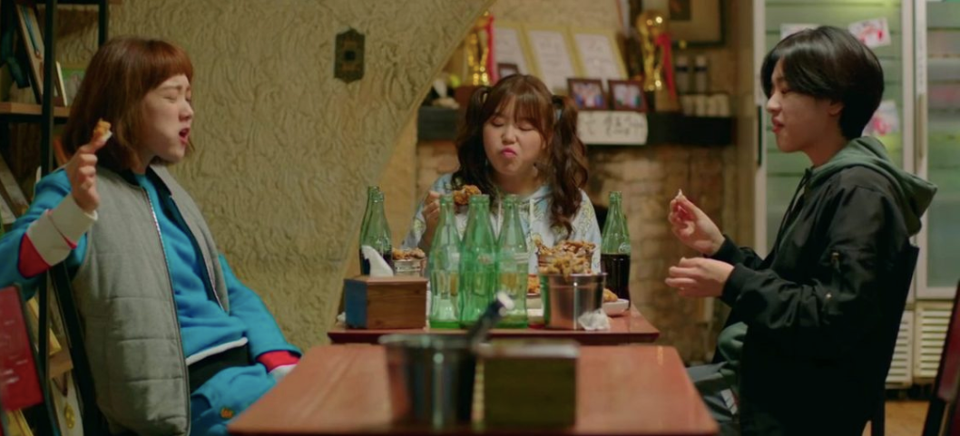 Three female college students eating fried chicken and drinking beer