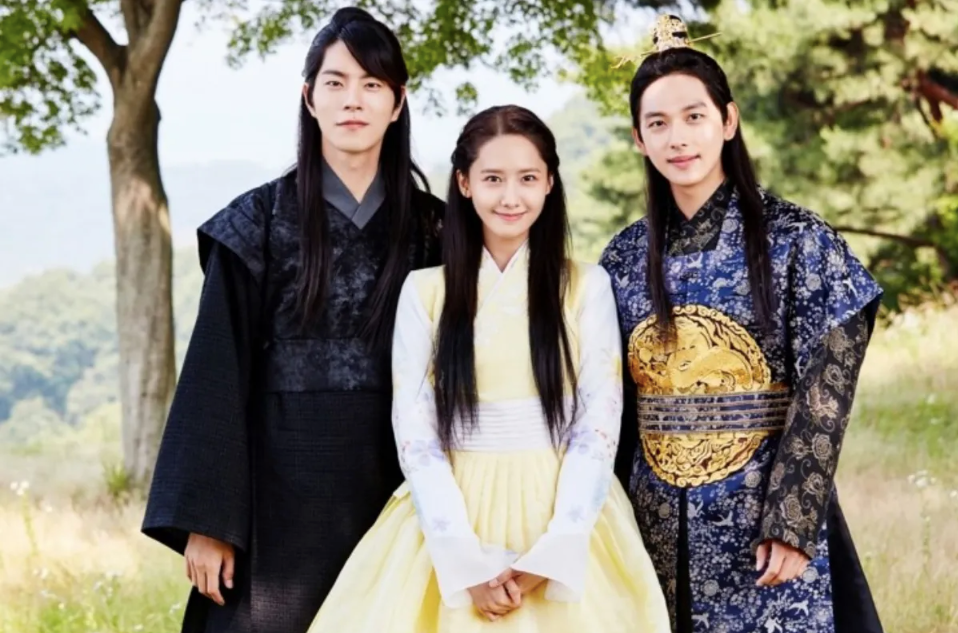 A woman in a yellow banbi with a man in a black hanbok and another man in a blue and gold hanbok