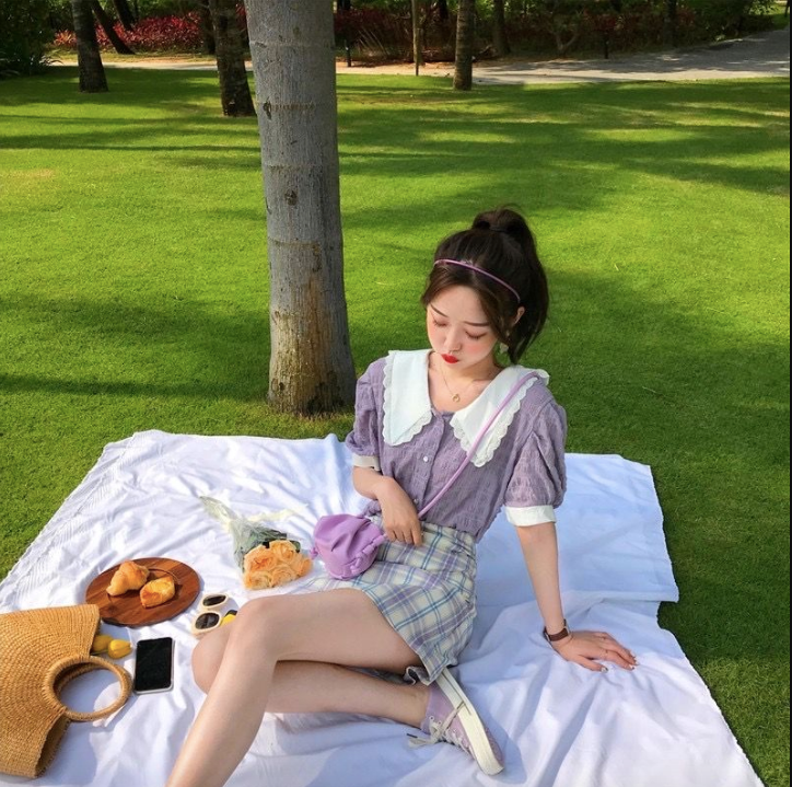 A girl wearing a cute outfit and purple purse on a white picnic blanket