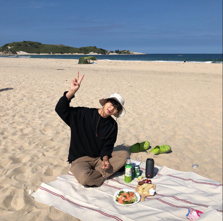 A man wearing a black sweater and a white hat at a picnic on a beach