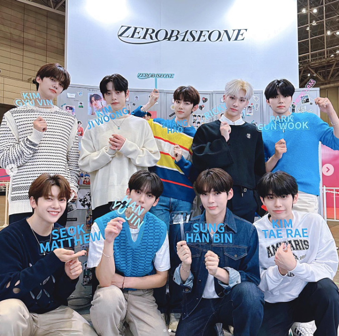 ZEROBASEONE members holding signs and lightsticks