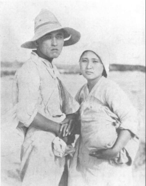 A man and woman dressed in peasant clothing looking forlornly into the camera