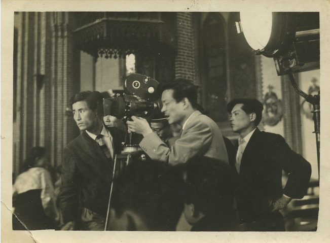 A man with a movie camera surrounded by crew