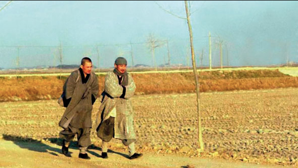 Two Buddhist monks walking through grain field