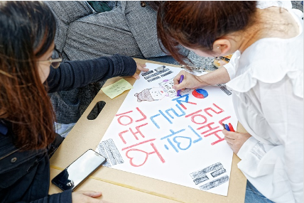 Two girls making a poster with Hangul