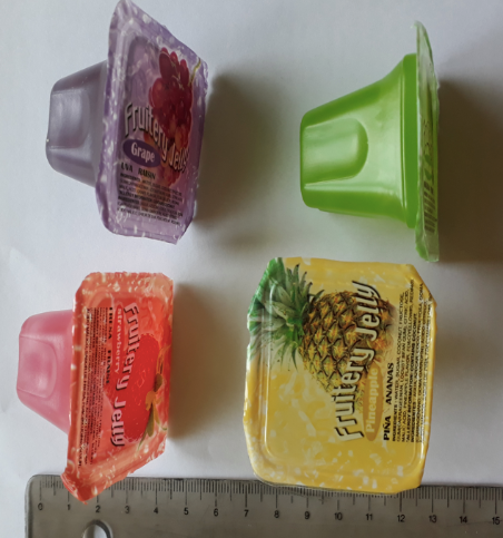 Four fruit jellies mainly on their sides above a metal ruler