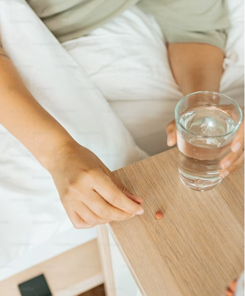 Person holding glass of water picking up tablet