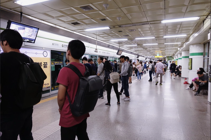 A mostly empty subway station with people waiting to board subway