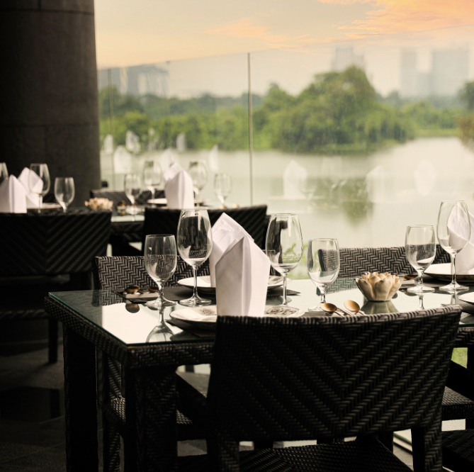 Black tables with crystal glasses and white napkins by a window