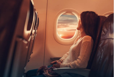 Woman looking out of plane window at sunset