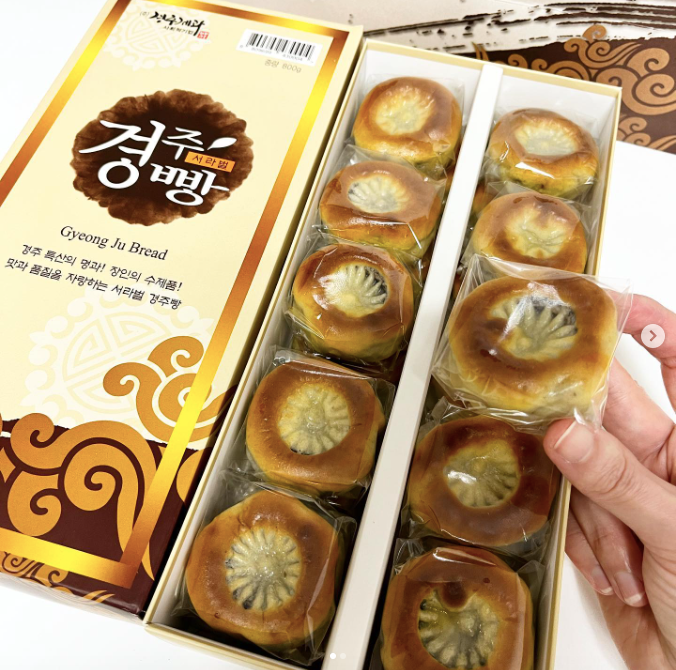 A hand holding a box with chrysanthemum-imprinted breads