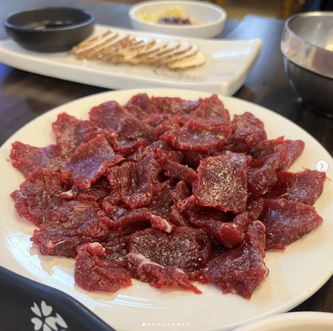 A white plate with sliced raw beef pieces