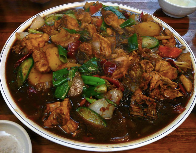 A metal bowl of spicy chicken and vegetables