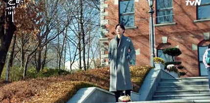 A man in a gray coat standing on stone steps of Konkuk University in the autumn 