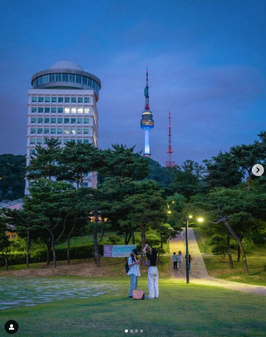 N Seoul Tower at dusk with two people standing facing it