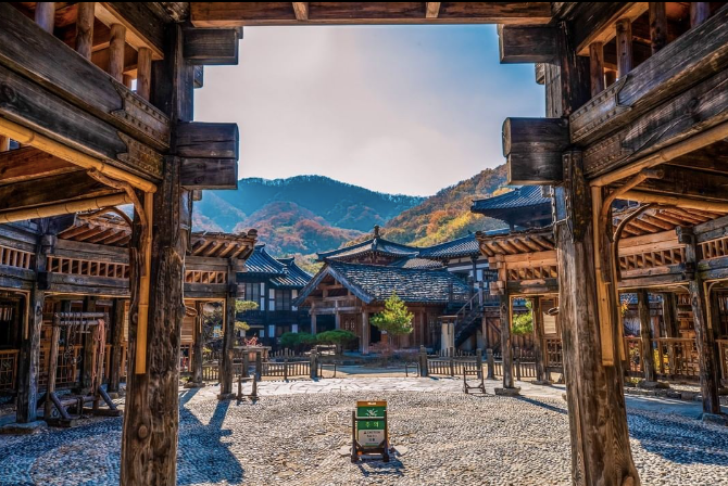 Wooden Korean palace structures facing a mountaintop and sign