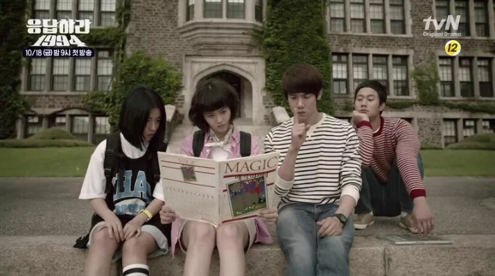 Four college students staring at map in front of ivy-covered school