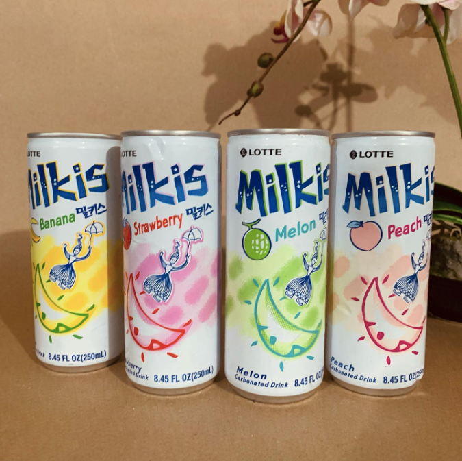 Yellow, pink, green, and orange Milkis cans with a brown background