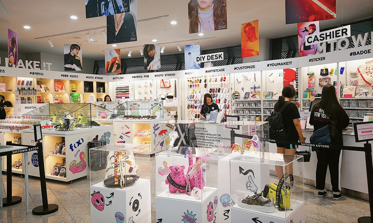 Interior of SM TOWN store with white displays, posters, and shoes