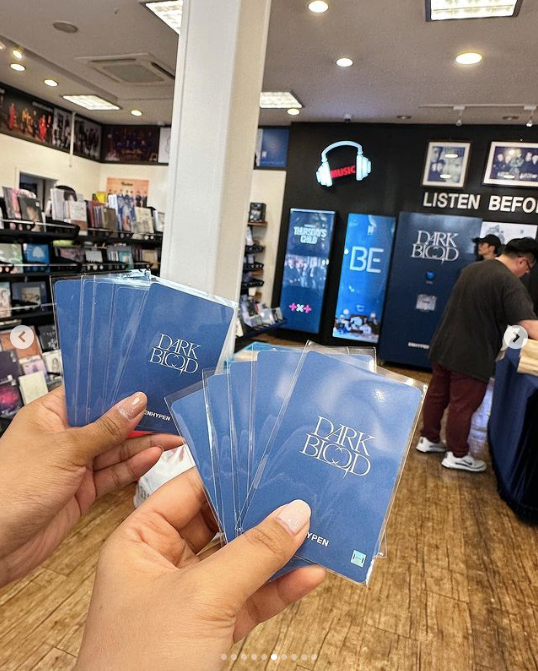 Two hands holding blue cards inside an M2U Record store