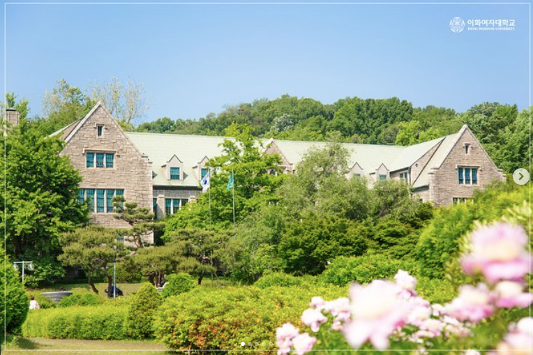 Ewha Womans University building with leafy trees and pink flowers