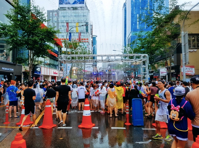 People standing on a wet street behind traffic cones at Sinchon Water Gun Festival