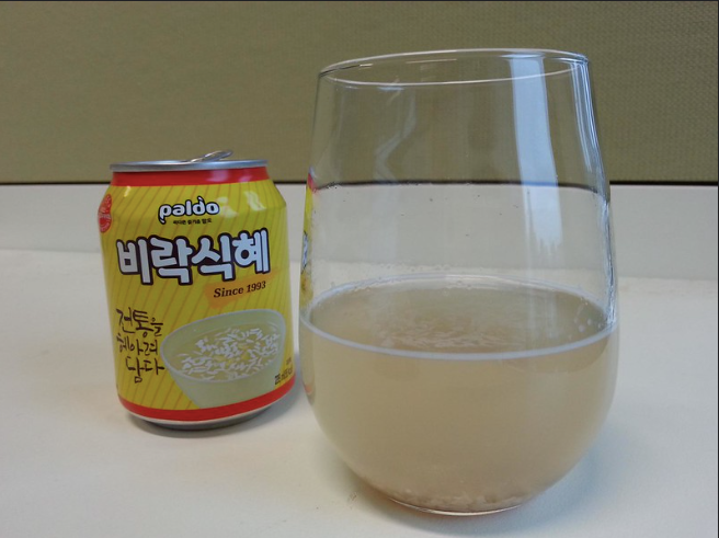 A glass of sikhye beside an opened can