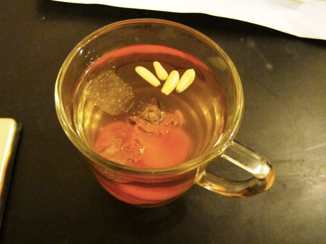A clear glass of sujjeongwa with seeds floating on top