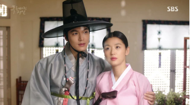 A man in a gut and gray hanbok and a woman in a pink hanbok