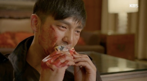 A man with blood on face and hands eating a Choco Pie