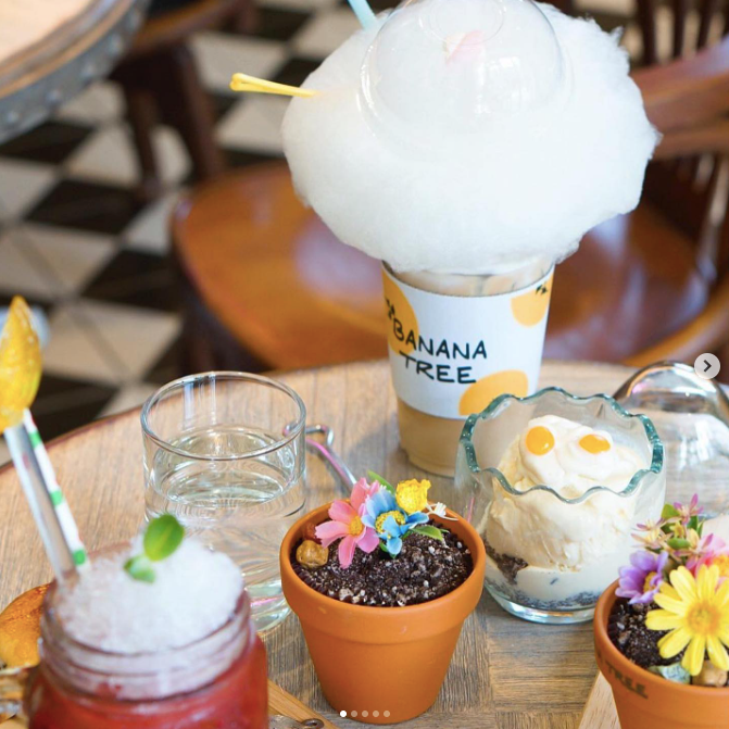 Glasses of drinks, cakes in flower pots, and a glass of fluffy candy cloud on a table