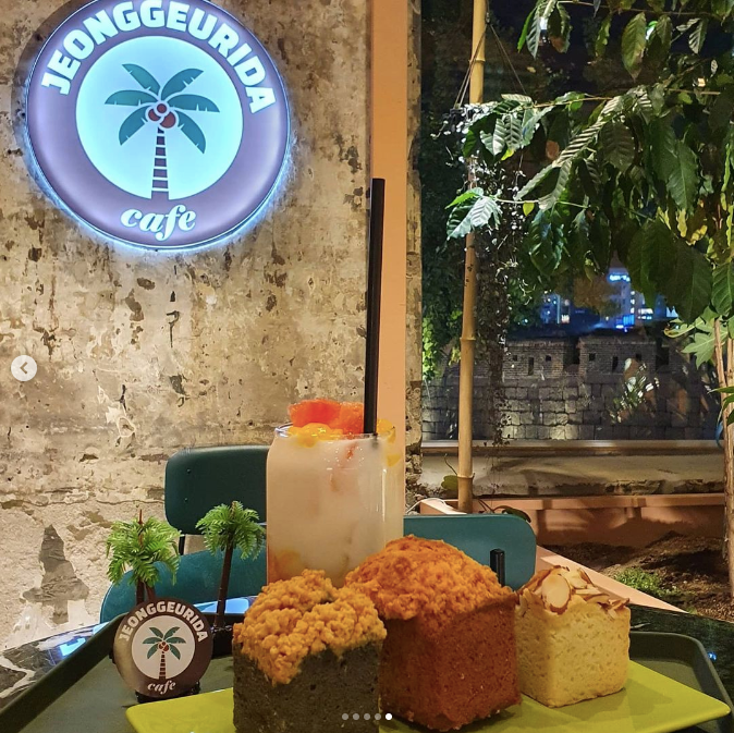 A tray of drinks and crumble-topped desserts under a light-up sign with a palm tree