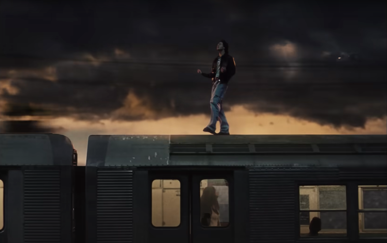 A man walking on top of a passenger car in which a woman is walking