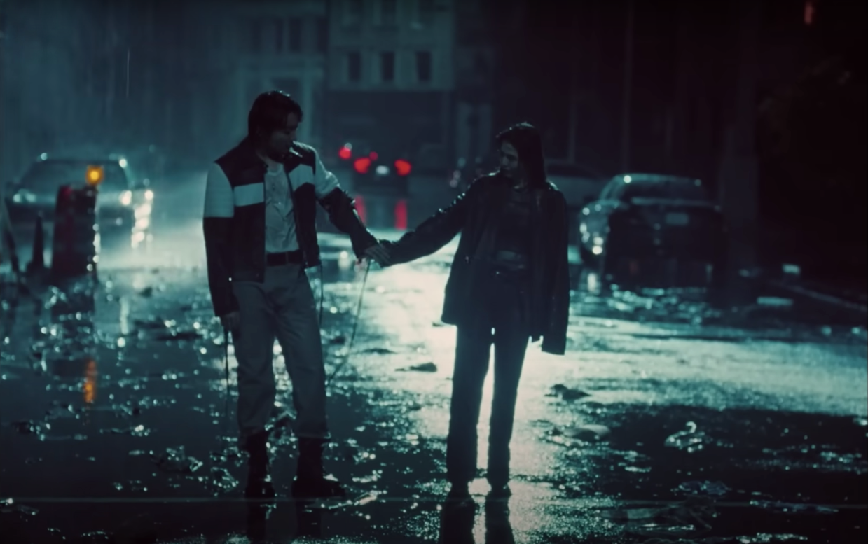 A man and woman holding hands on a dark rain-soaked street