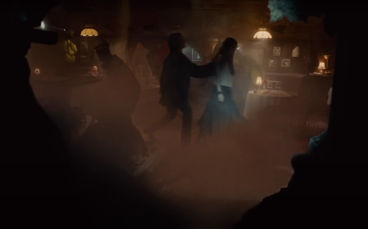 A man and a woman walking in a dust-filled room