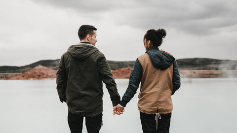 A couple holding hands in front of a lagoon