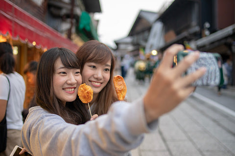 Young female friends taking selfie picture with senbei.