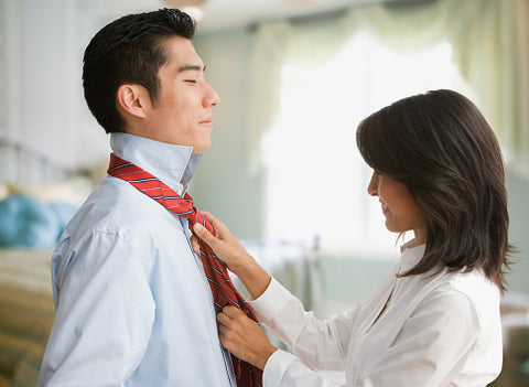 Eurasian woman tying Korean man's tie