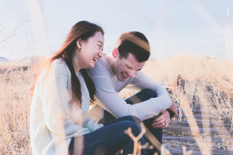 An interracial couple sitting in a wheat field