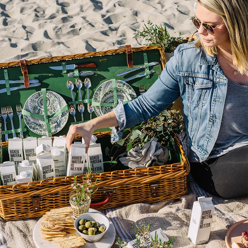 women hosted a beach picnic with several cartons of orginal flavor boxed water