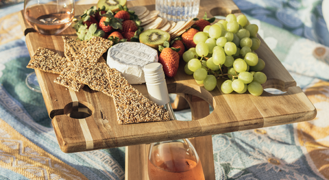 Picnic platter of fresh summer fruits and a bottle of rose.