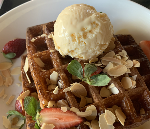 Waffles topped with icecream, strawberries and slivered almonds