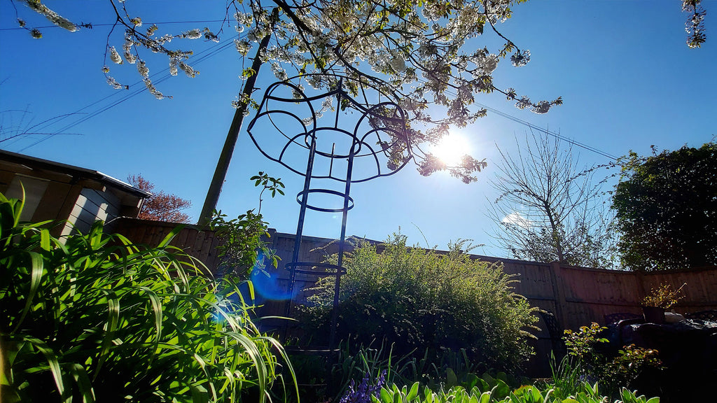 metal obelisk against the blue sky in a garden