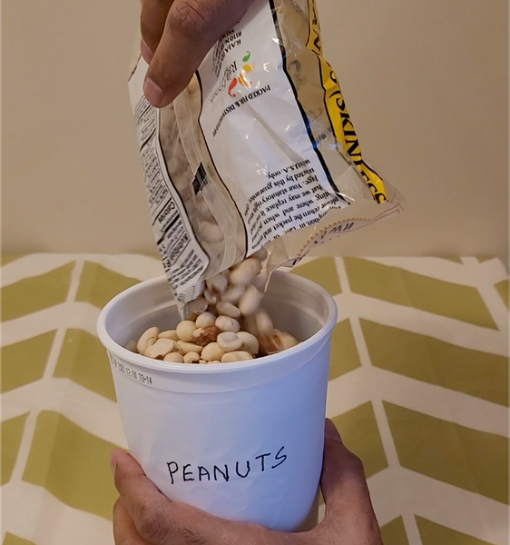 Image showing the storage of peanuts in a repurposed and labeled yogurt container.