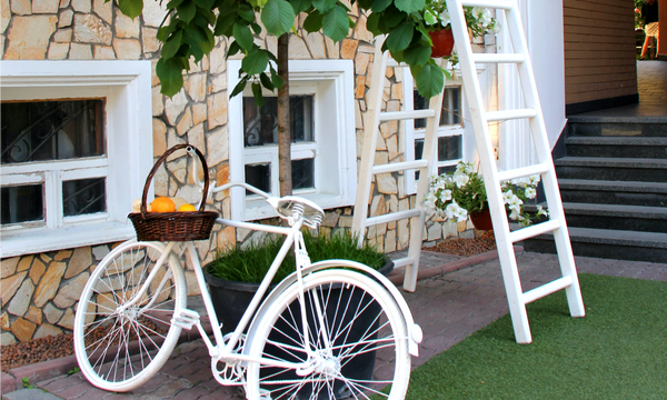 summer patio with hanging flower pots and a white bicycle leaning against a tree